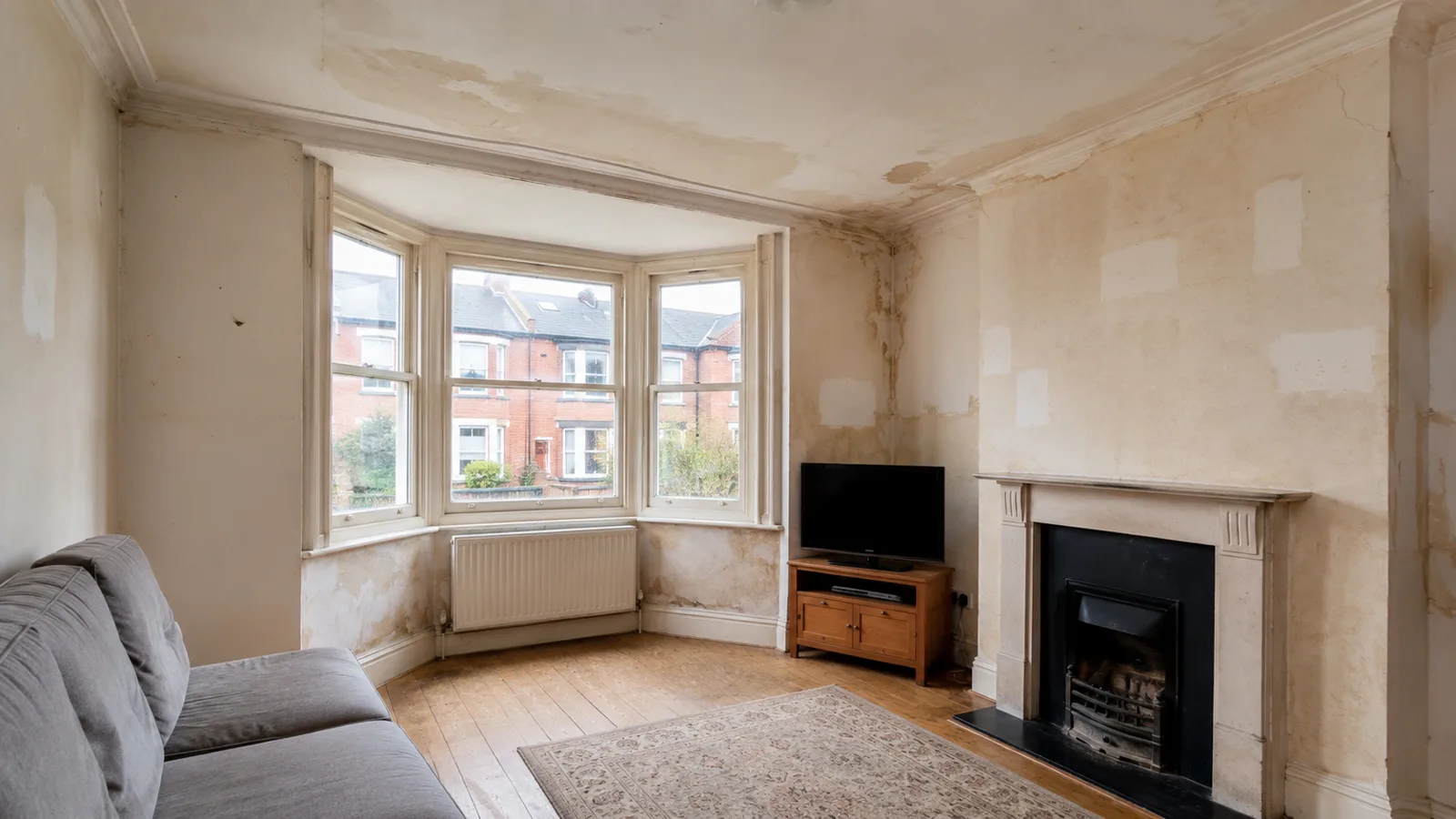 Lounge before repainting, showing bare and stained plaster